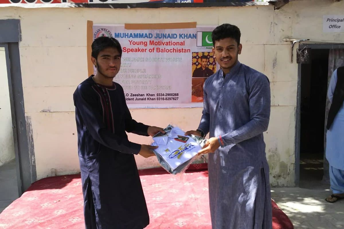 Clothing being handed to a young man outside a school office.