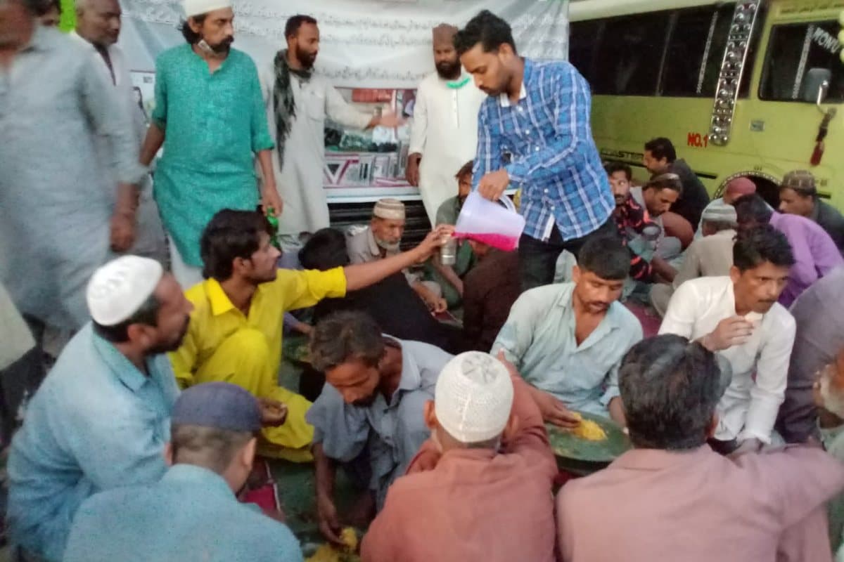 A volunteer pouring drinks for people seated at the meal.