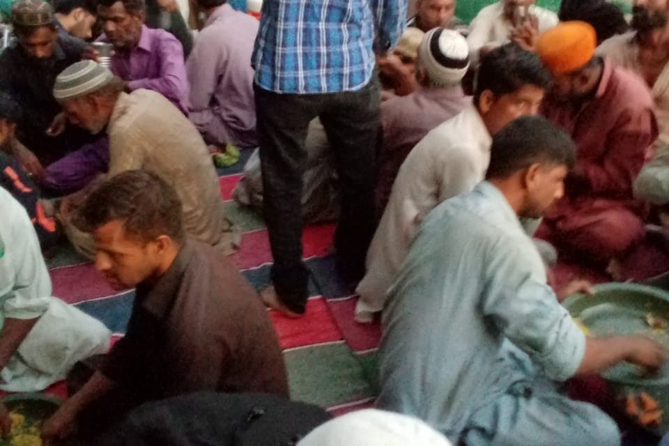 Volunteers moving among people seated eating in the street.