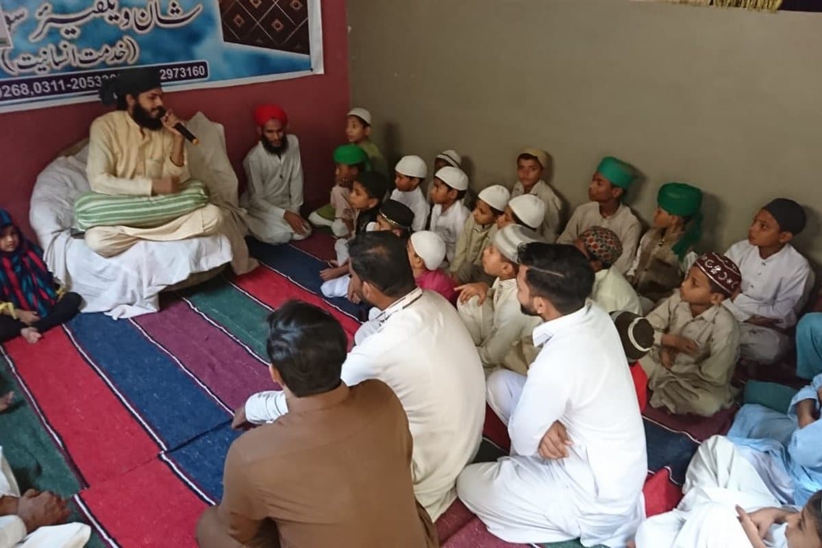 A madrasa class in session under a Shaan Welfare banner.