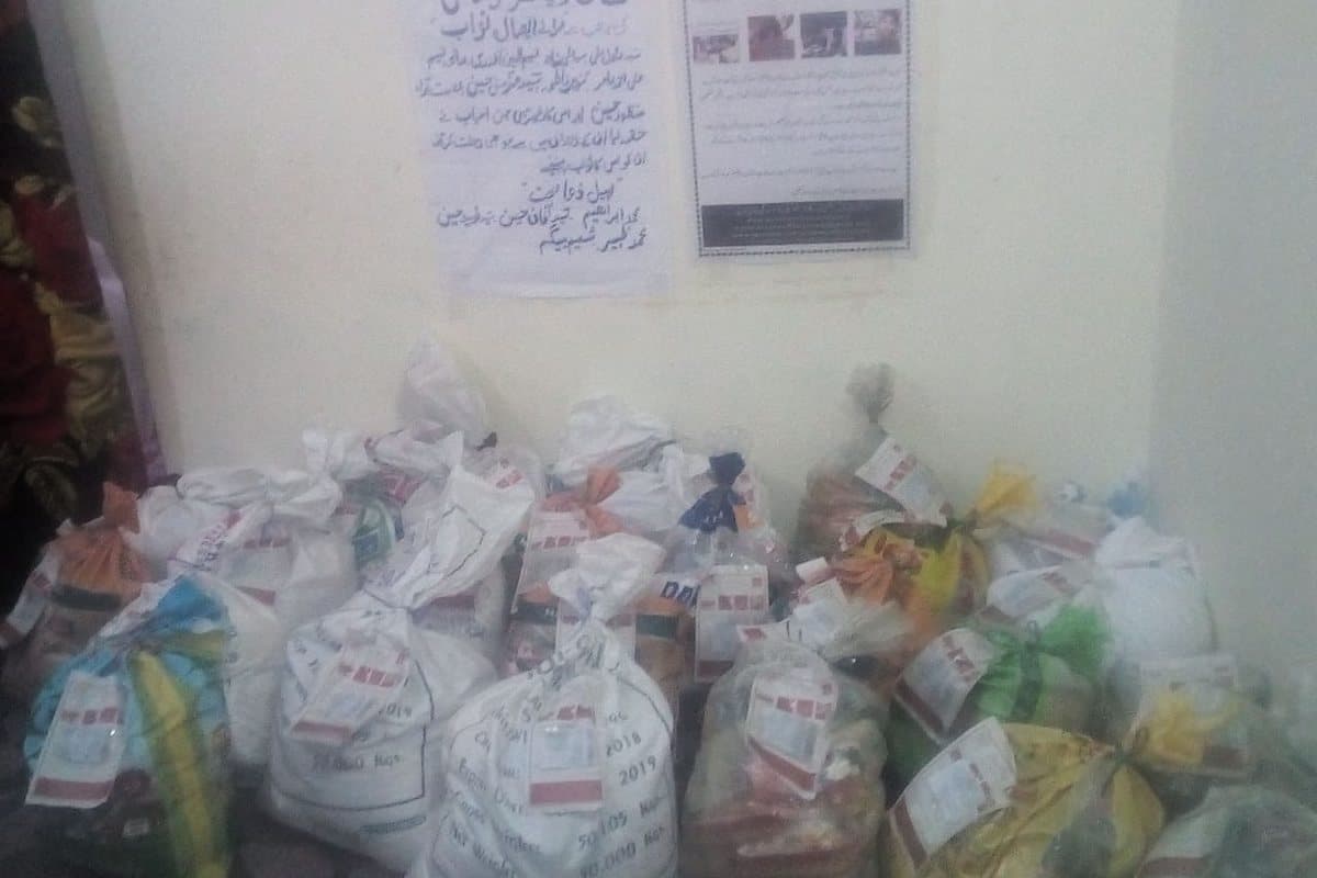 Ration bags stacked indoors beneath Shaan Welfare notices.